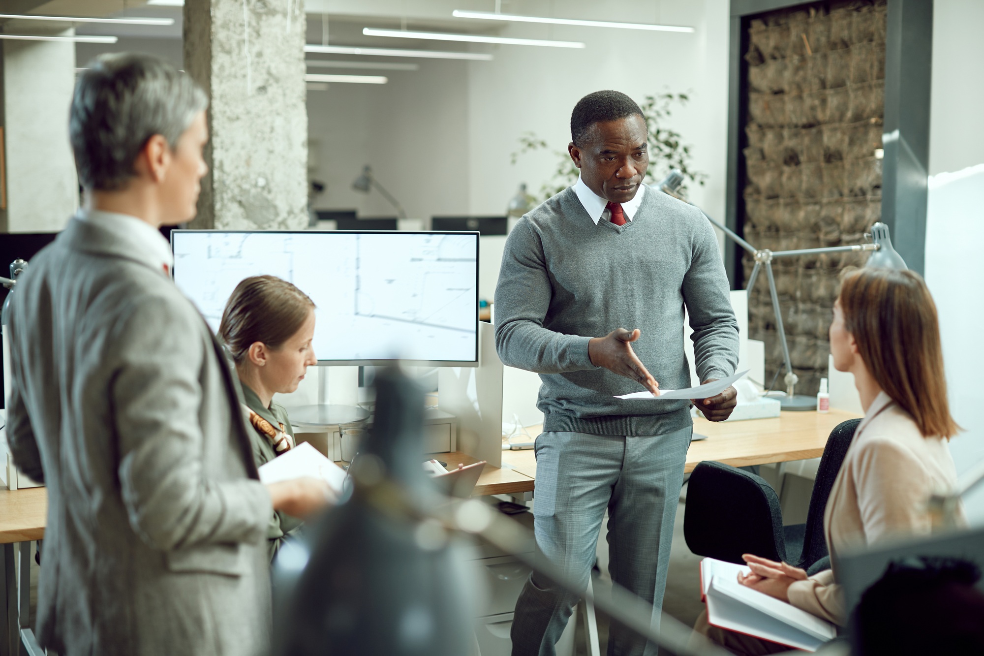 African American CEO analyzing business reports with his team during a briefing in the office.